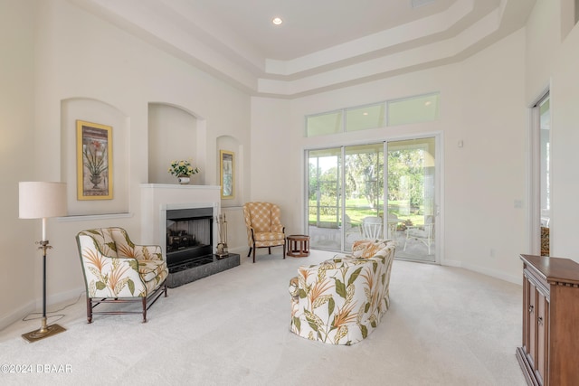 living area with a towering ceiling, light carpet, and a tray ceiling