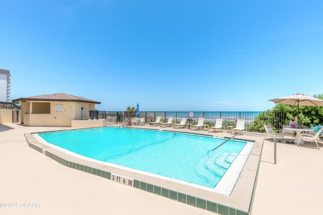 view of swimming pool with a water view and a patio area