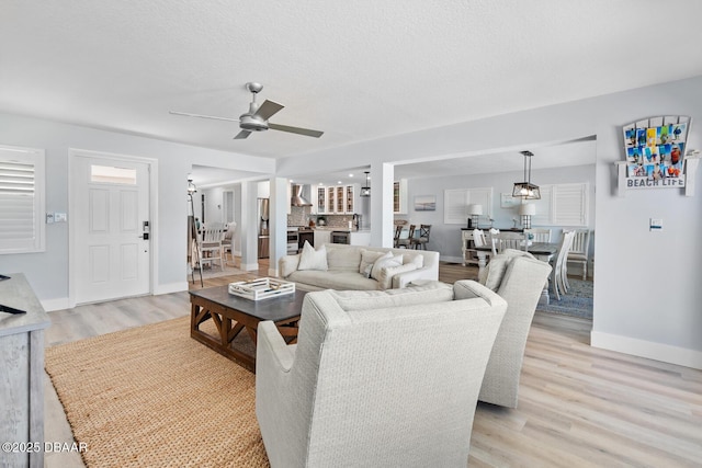 living room featuring light wood-type flooring, ceiling fan, and a textured ceiling