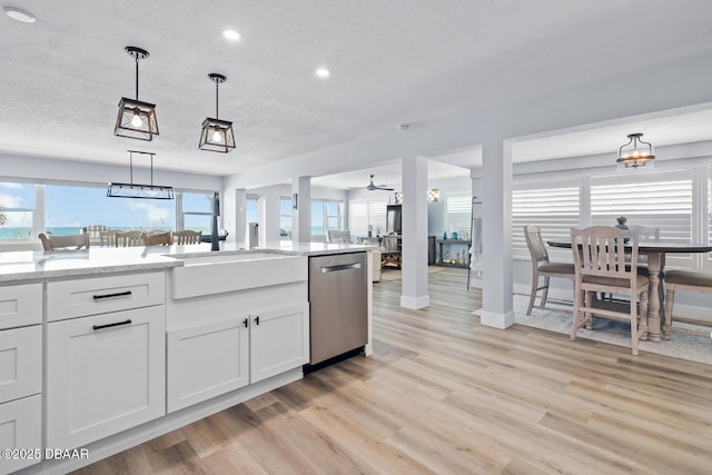 kitchen featuring a textured ceiling, white cabinetry, sink, hanging light fixtures, and stainless steel dishwasher