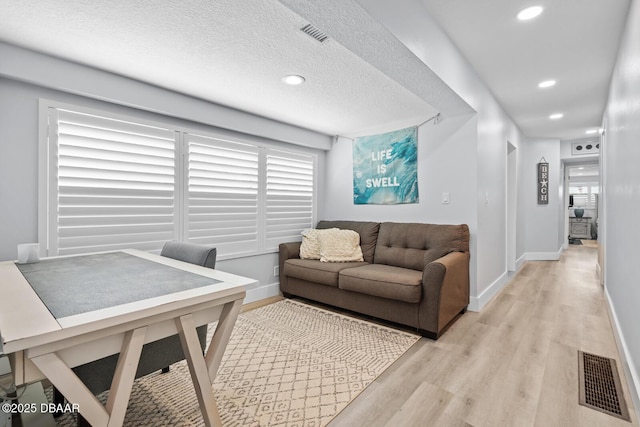 living room with a textured ceiling and light wood-type flooring