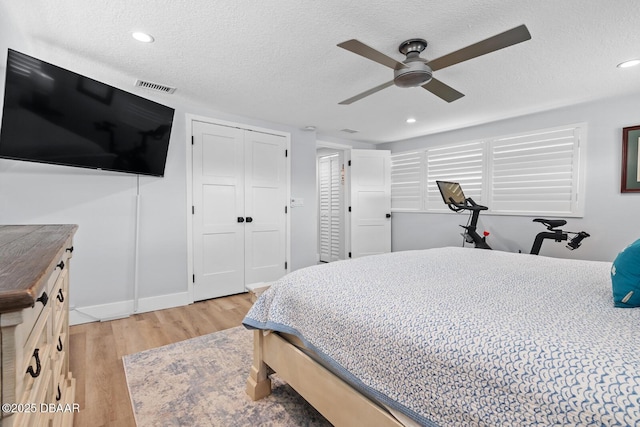 bedroom with a textured ceiling, ceiling fan, a closet, and light hardwood / wood-style flooring