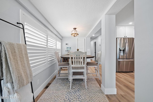 dining room featuring a chandelier, light hardwood / wood-style floors, and a textured ceiling