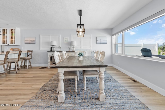 dining area with light wood-type flooring and a textured ceiling