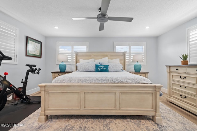 bedroom with ceiling fan, hardwood / wood-style floors, and a textured ceiling