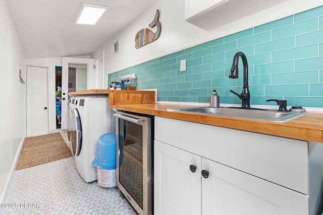 clothes washing area featuring beverage cooler, indoor wet bar, and washer and dryer