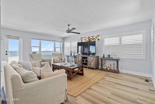 living room with light hardwood / wood-style floors, a textured ceiling, and ceiling fan