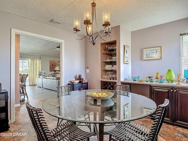 31 Sea Harbor Dr E Unit E, Ormond Beach, FL 32176 - dining room with a textured ceiling, a ceiling fan, a chandelier, and light stone finish floors