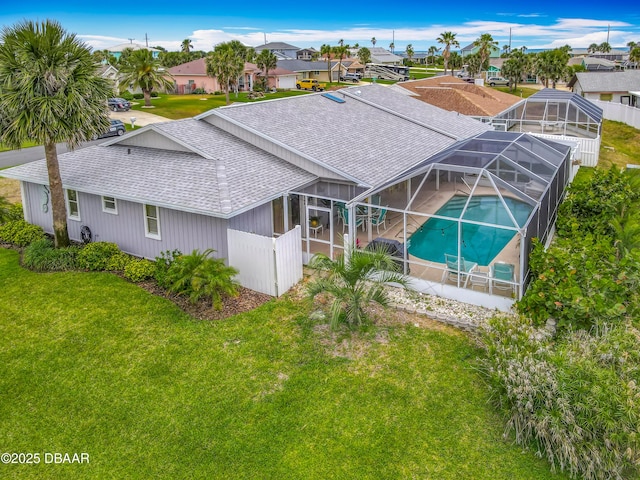 31 Sea Harbor Dr E Unit E, Ormond Beach, FL 32176 - back of house featuring a shingled roof, an outdoor pool, a residential view, a lawn, and a lanai