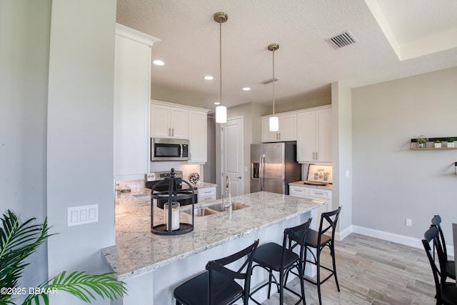 kitchen featuring appliances with stainless steel finishes, pendant lighting, white cabinets, and kitchen peninsula