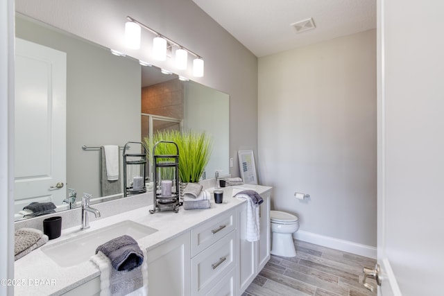 bathroom featuring a shower with door, vanity, a textured ceiling, and toilet