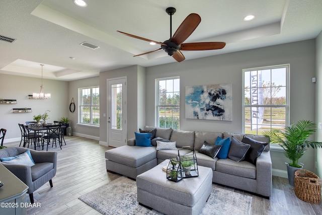 living room featuring a raised ceiling, light hardwood / wood-style floors, and a wealth of natural light