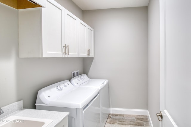 washroom with cabinets, washing machine and clothes dryer, and sink