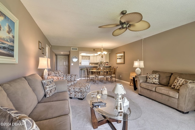 living room featuring ceiling fan with notable chandelier, a textured ceiling, and light carpet