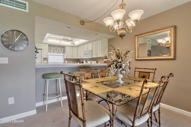 dining space featuring a textured ceiling, light carpet, and ceiling fan with notable chandelier