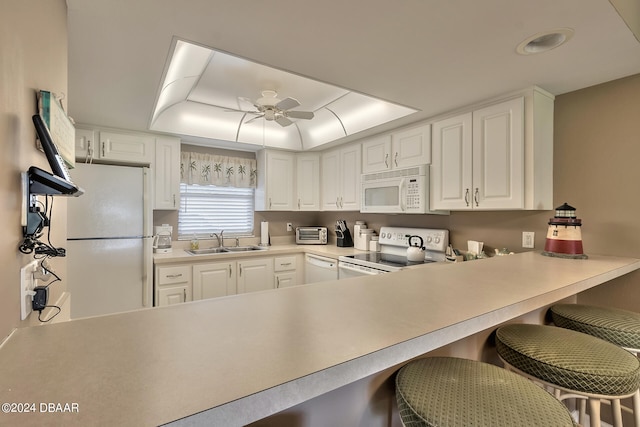 kitchen featuring white cabinetry, a kitchen breakfast bar, sink, and white appliances