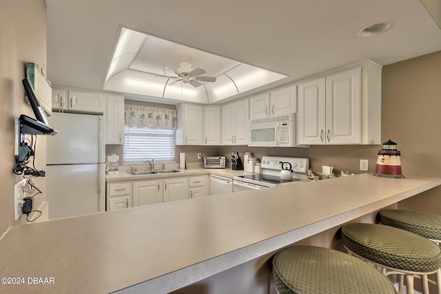 2100 Ocean Shore Blvd Unit 109, Ormond Beach, FL 32176 - kitchen featuring white appliances, a sink, a kitchen bar, white cabinetry, and a peninsula