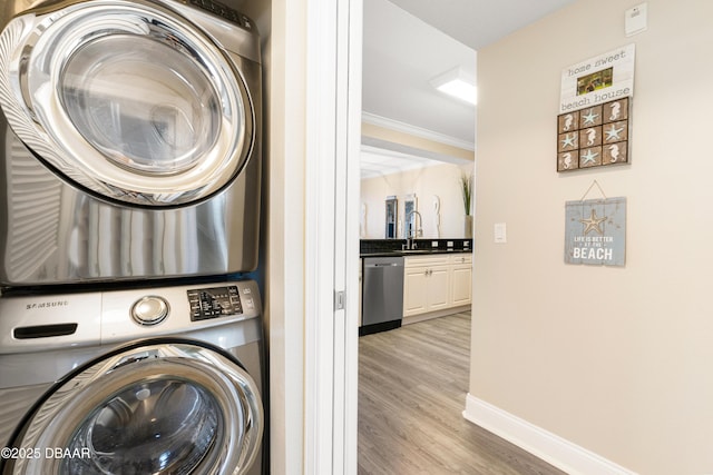 laundry area with crown molding, sink, light hardwood / wood-style flooring, and stacked washer and clothes dryer