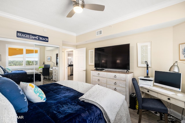 bedroom featuring ceiling fan, wood-type flooring, crown molding, and a closet