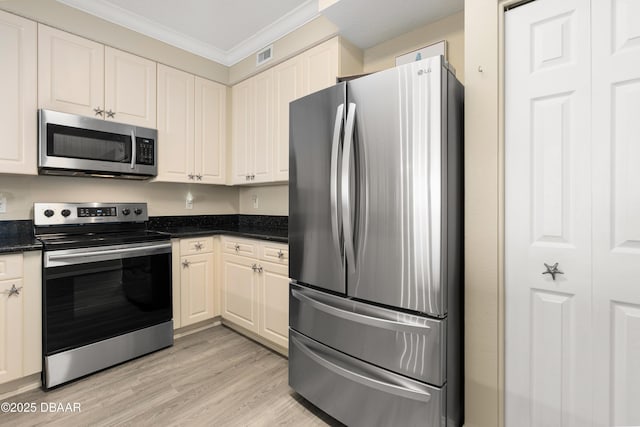 kitchen with crown molding, stainless steel appliances, dark stone counters, and light hardwood / wood-style flooring