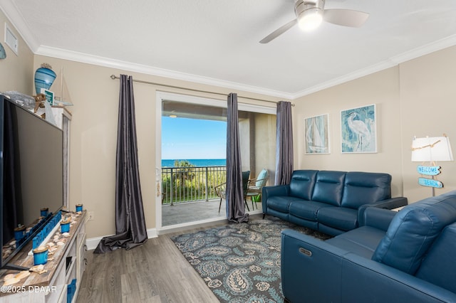 living room featuring ceiling fan, a water view, wood-type flooring, and crown molding