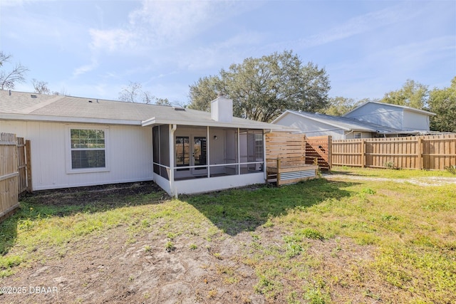 rear view of house featuring a yard and a sunroom