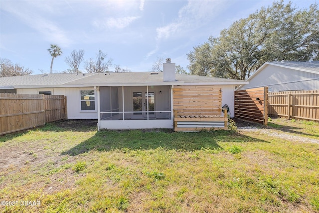 rear view of property featuring a lawn and a sunroom