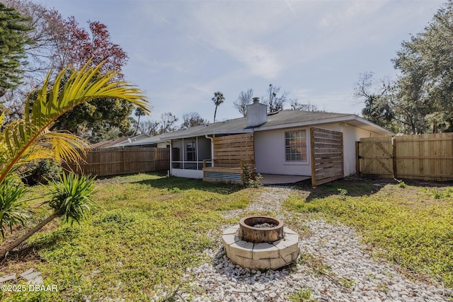 back of house with a fire pit, a lawn, and a sunroom