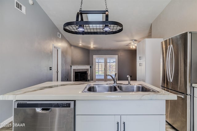 kitchen featuring sink, ceiling fan, appliances with stainless steel finishes, white cabinetry, and an island with sink