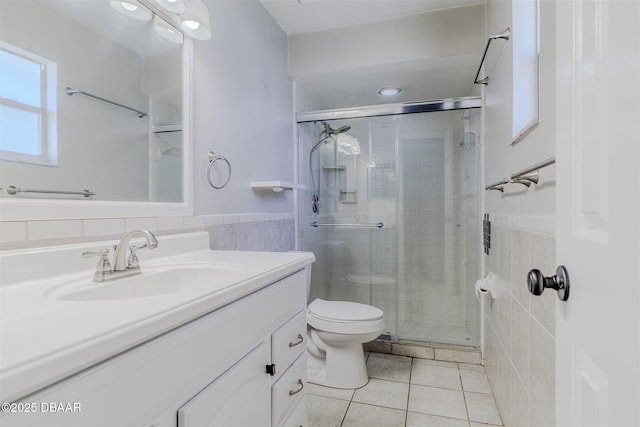 bathroom with tile walls, vanity, a shower with shower door, tile patterned floors, and toilet