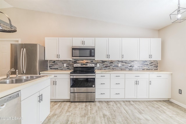 kitchen featuring white cabinetry, stainless steel appliances, vaulted ceiling, and sink