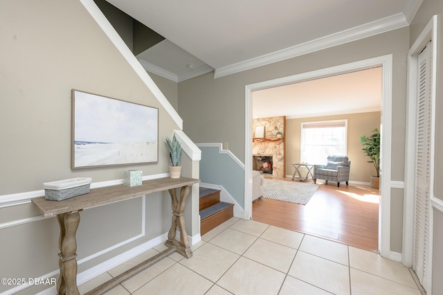 tiled foyer with ornamental molding and a fireplace