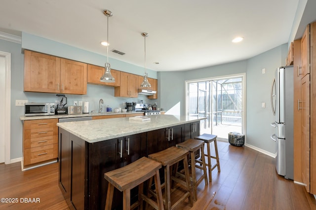 kitchen with hanging light fixtures, sink, a center island, and appliances with stainless steel finishes