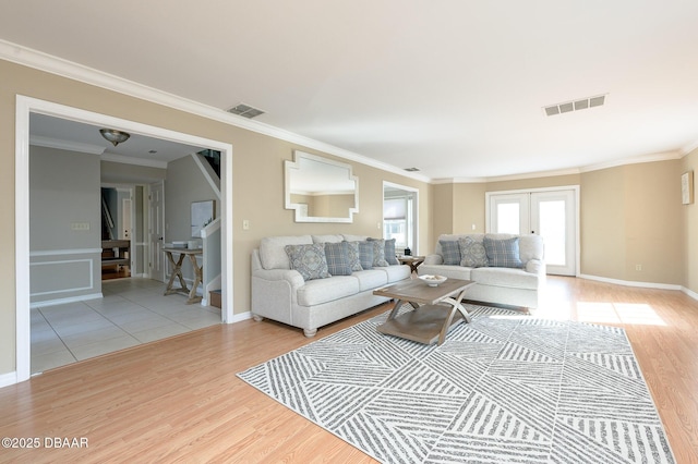 living room with crown molding, light hardwood / wood-style flooring, and french doors