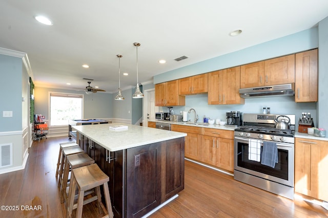 kitchen featuring a kitchen island, decorative light fixtures, sink, a kitchen breakfast bar, and stainless steel appliances