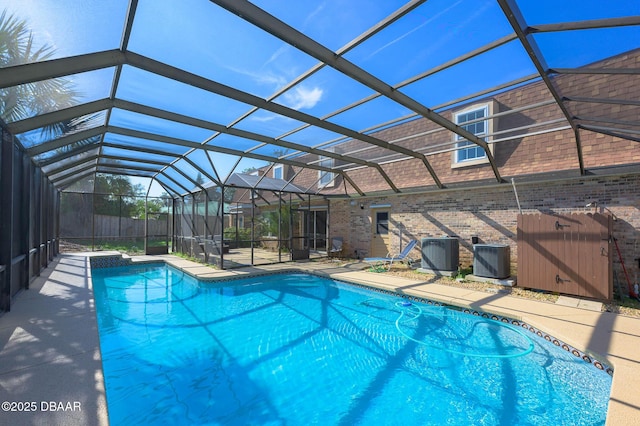 view of swimming pool with a patio, central AC, and glass enclosure