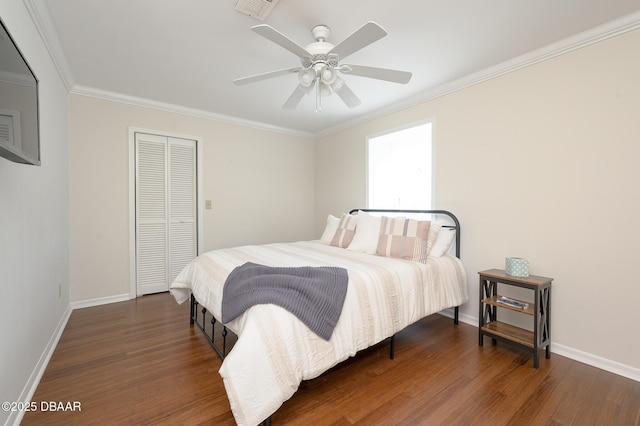 bedroom featuring dark wood-type flooring, ornamental molding, a closet, and ceiling fan