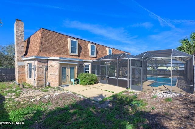 rear view of property featuring a fenced in pool, glass enclosure, french doors, and a patio area