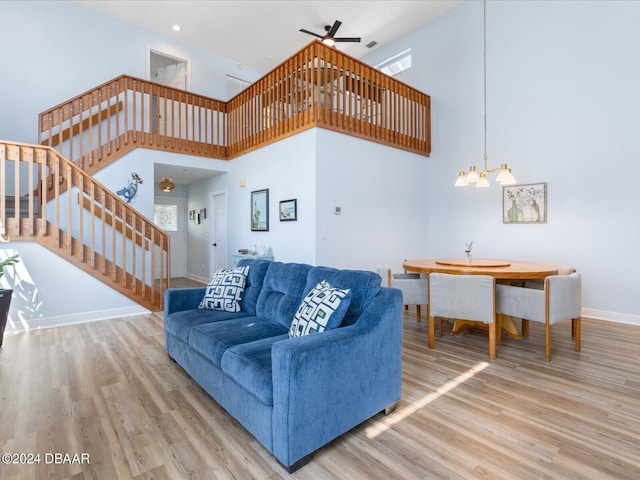 living room with ceiling fan with notable chandelier, stairway, baseboards, and wood finished floors