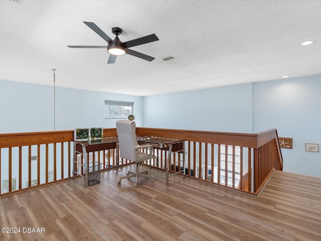 hallway featuring light wood-type flooring, visible vents, a textured ceiling, and recessed lighting