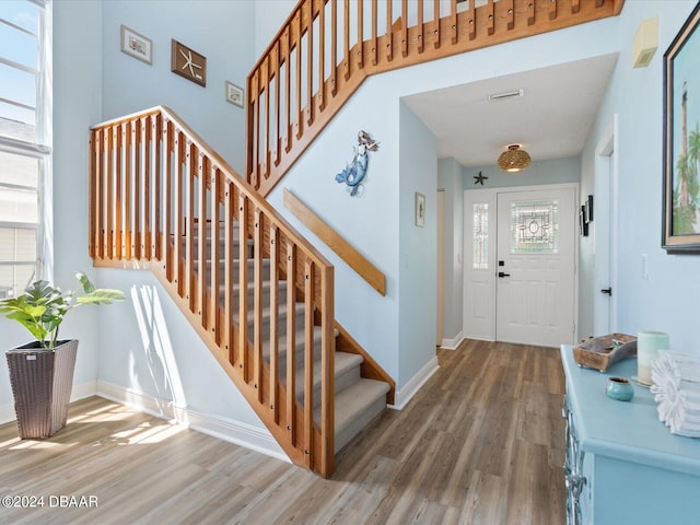 foyer with stairs, a healthy amount of sunlight, baseboards, and wood finished floors