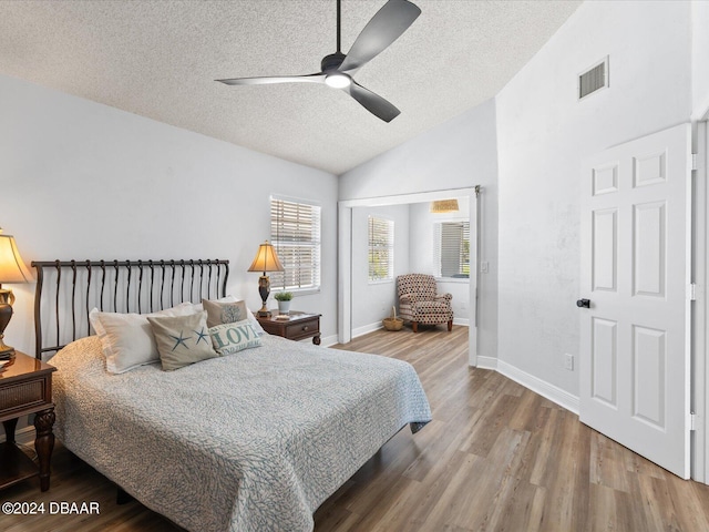 bedroom featuring lofted ceiling, a textured ceiling, hardwood / wood-style flooring, and ceiling fan