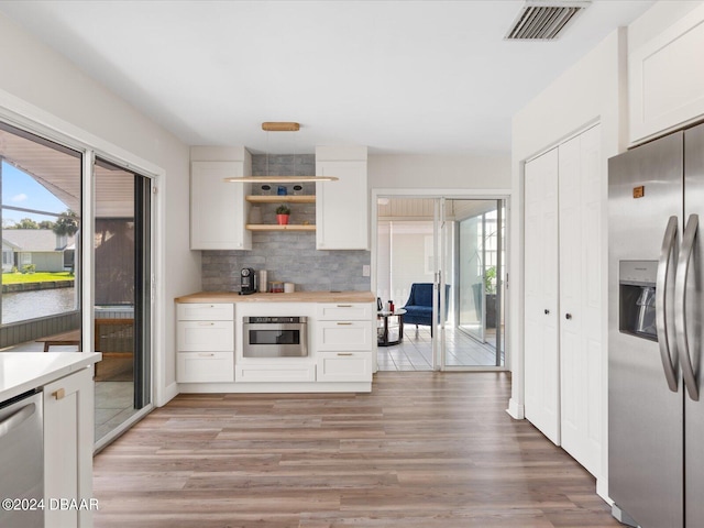 kitchen featuring white cabinetry, light wood-type flooring, tasteful backsplash, and stainless steel appliances