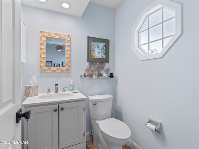 half bath with toilet, recessed lighting, and vanity