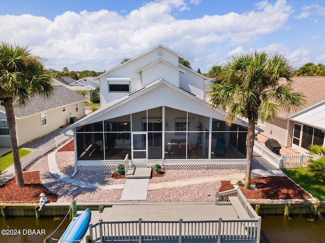 back of property featuring a sunroom and a water view