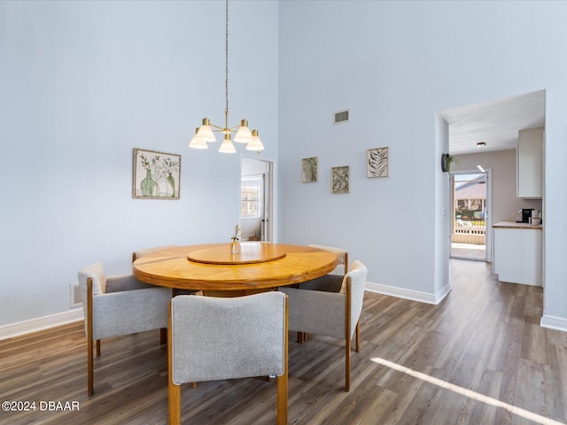 dining space featuring a chandelier, a towering ceiling, visible vents, baseboards, and dark wood-style floors