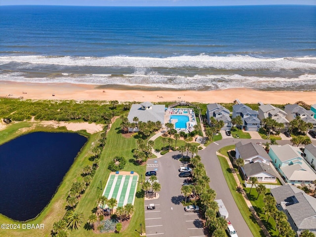 drone / aerial view featuring a water view, a residential view, and a beach view