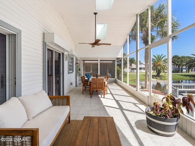 sunroom featuring vaulted ceiling, ceiling fan, and a water view