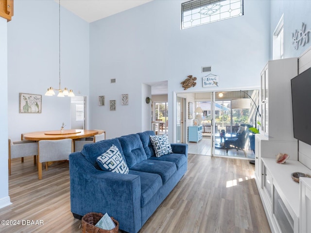 living room with hardwood / wood-style floors, a notable chandelier, and a towering ceiling