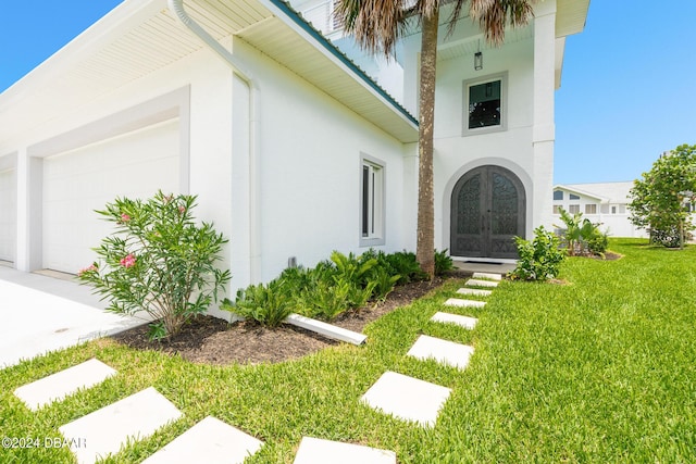 4727 Riverglen Blvd, Ponce Inlet, FL 32127 - view of side of home featuring french doors, stucco siding, an attached garage, and a lawn